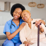 Black woman, nurse and senior patient in elderly care, hug and healthcare on living room sofa at ho.