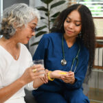 Healthcare worker or caregiver explaining medicine dosage to senior woman. Elderly healthcare concept.