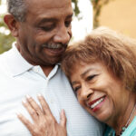 Senior black husband and wife embracing outdoors, close up