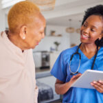 Tablet, senior black woman and nurse in home for healthcare, support and help. Caregiver, technolog.